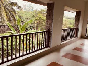 a room with a balcony with a view of a garden at Joppa House in Kanyakumari