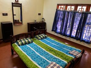 a bedroom with a bed with a mirror and curtains at Joppa House in Kanyakumari