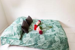 ein Bett mit zwei Kissen und Blumen darauf in der Unterkunft studio lumineux in Choisy-le-Roi