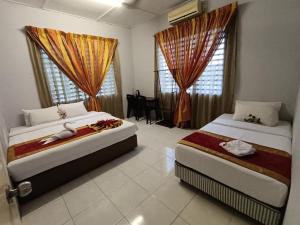 a bedroom with two beds and a table in it at Taman Bahagia Homestay in Temerloh