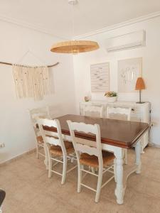a dining room with a wooden table and white chairs at Casa en el Centro de Cabo de Palos Cerca a Clubes de Buceo in Cabo de Palos
