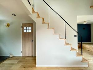 a staircase in a house with white walls and wooden floors at Spruce Cottage in Yuzawa
