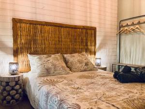 Schlafzimmer mit einem großen Bett mit einem Kopfteil aus Holz in der Unterkunft Mika & Clo in Saint-Joseph
