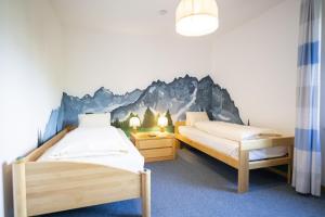 two beds in a room with a mountain mural on the wall at Chasa La Plavna Willeke in Vulpera