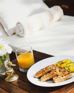 a plate of toast and fruit and a glass of orange juice at Taru Villas Kandy in Kandy