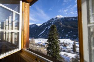 una ventana con vistas a una montaña nevada en Chasa Schilana 84 en Ramosch