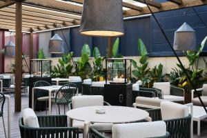um restaurante com mesas brancas, cadeiras e plantas em Catalonia La Maquinista em Barcelona