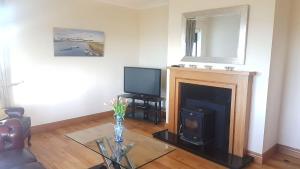 a living room with a fireplace and a tv at Coral Strand Lodge in Ballyconneely