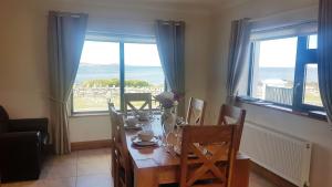a dining room with a table and chairs and windows at Coral Strand Lodge in Ballyconneely