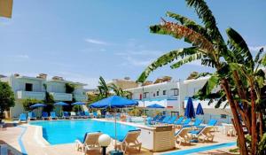 a swimming pool with chairs and blue umbrellas at Kosinmyheart Apartment 11 & Studio10 in Kos