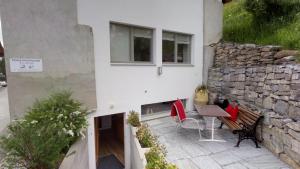 a patio with a table and chairs and a stone wall at Chasa Samalgors in Tschlin 