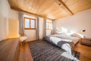 1 dormitorio con cama grande y techo de madera en Chasa Pro la Tuor en Ardez