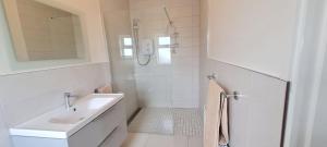 une salle de bain blanche avec lavabo et douche dans l'établissement Foregloss Cottage, à Ballyconneely 12 autres photos