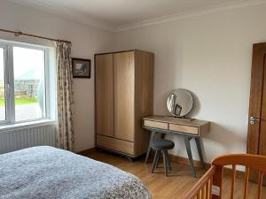 une chambre avec un lit et un bureau avec un miroir dans l'établissement Foregloss Cottage, à Ballyconneely