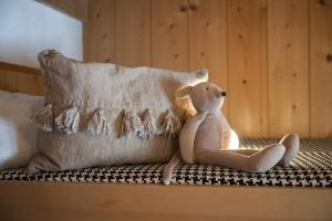 un osito de peluche sentado en una cama junto a una almohada en Chasa Riatsch, en Ardez