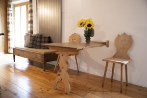 una mesa de madera con un jarrón de flores encima en Chasa Riatsch, en Ardez
