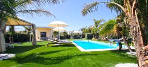 podwórko z basenem i palmami w obiekcie Villa Gisira - Luxury SPA w mieście Brucoli