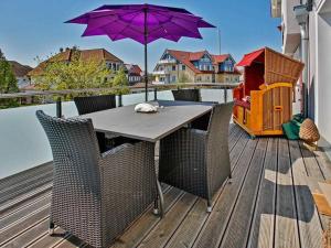 stół i krzesła na tarasie z fioletowym parasolem w obiekcie Frauke im Anker w Zingst