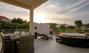 eine Terrasse mit einem Whirlpool, einem Tisch und Stühlen in der Unterkunft Villa Kora - luxury holiday Apartments in Lumbarda