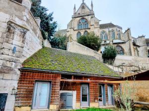 un vecchio edificio con un tetto ricoperto di edera di fronte a una chiesa di Home - Saint Loup - Séjour à Auxerre ad Auxerre