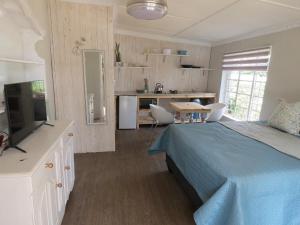 a bedroom with a blue bed and a kitchen at Avalon Cottages in Barberton