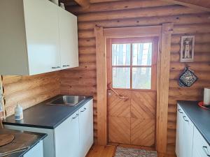 a kitchen with a door in a log cabin at Velkuanmaa Lomamökki in Naantali