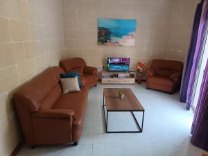 uma sala de estar com dois sofás e uma televisão em Hideaway Flats em Xlendi