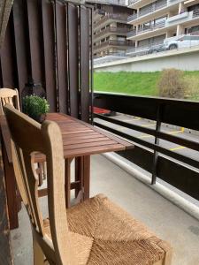 einen Holztisch und einen Stuhl auf dem Balkon in der Unterkunft Le Tortin - studio centré et calme - 2 personnes in Nendaz