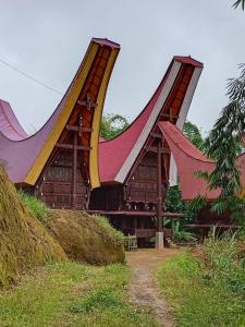 een gebouw met gebogen daken op een veld bij The Twins Homestay in Rantepao