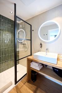 ein Bad mit einem Waschbecken und einer Dusche in der Unterkunft Hotel La Malle Poste in Rochefort