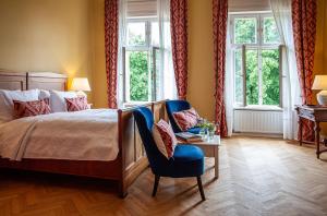 a bedroom with a bed and a chair and windows at Schlosshotel Ziethen in Kremmen