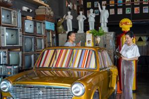 duas mulheres ao lado de um carro amarelo numa loja em Quip Bed & Breakfast em Cidade Phuket