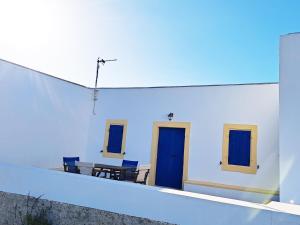 a white building with blue doors and a table at Sophie's Pourko House in Kythira