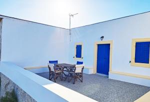 a patio with a table and chairs and a blue wall at Sophie's Pourko House in Kythira