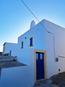a white building with a blue door on it at Sophie's Pourko House in Kythira