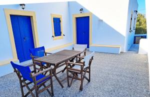 a wooden table and chairs on a patio with blue doors at Sophie's Pourko House in Kythira