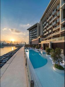 a large building with a swimming pool next to the water at Hyatt Centric Jumeirah Dubai - King Room - UAE in Dubai