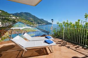 Un balcón con una silla blanca y vistas al agua. en Ravello Art Hotel Marmorata, en Ravello