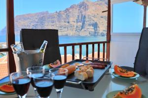 a table with a tray of food and glasses of wine at Capitain Beachside Haven in Acantilado de los Gigantes