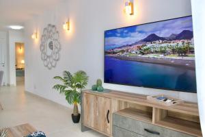 a living room with a large flat screen tv on a wall at Capitain Beachside Haven in Acantilado de los Gigantes