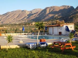 a pool with a table and chairs and mountains at Flisvos Apartments in Frangokastello