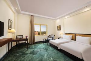 um quarto de hotel com duas camas e uma secretária em V Sarovar Portico MI Road Jaipur em Jaipur