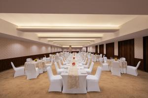 a long banquet hall with white tables and white chairs at V Sarovar Portico MI Road Jaipur in Jaipur