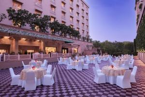 um salão de banquetes com mesas brancas e cadeiras brancas em V Sarovar Portico MI Road Jaipur em Jaipur
