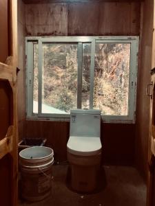 a bathroom with a toilet and a window at Hotel waterfall,Benkar in Phakding