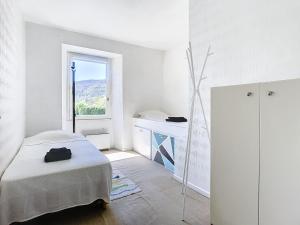 a white bedroom with a bed and a window at Authenticité, jardin, terrasse et vue in Chanac