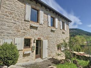a stone house with wooden doors and windows at Authenticité, jardin, terrasse et vue in Chanac
