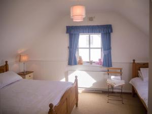 a bedroom with two beds and a window at 14 Leitirshask, Ballyconneely in Ballyconneely