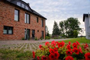 een bakstenen huis met rode bloemen ervoor bij Liepgarten bei Ueckermünde Fewo 15 - Zum Kolk in Ueckermünde