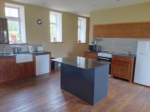 cocina con suelo de madera y nevera blanca en Upper Yard Borris House, en Borris